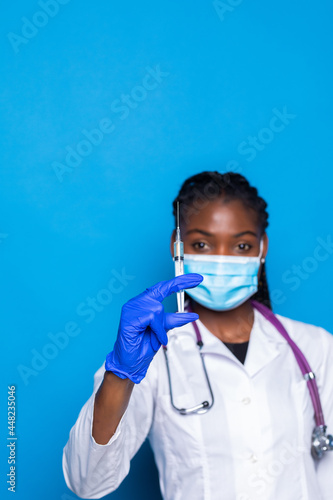 healthcare, vaccination, anesthesia and medical concept - african american female doctor holding syringe with injection isolated over blue background