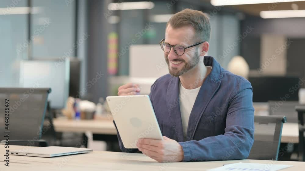 Middle Aged Businessman Celebrating Success on Tablet in Office Middle Aged Businessman Celebrating Success on Tablet in Office