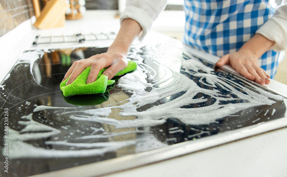 Obraz premium Woman is cleaning black induction stove.