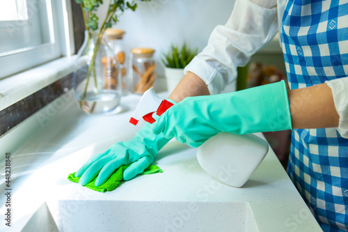 Woman cleaning kitchen top with rag and spray cleaner