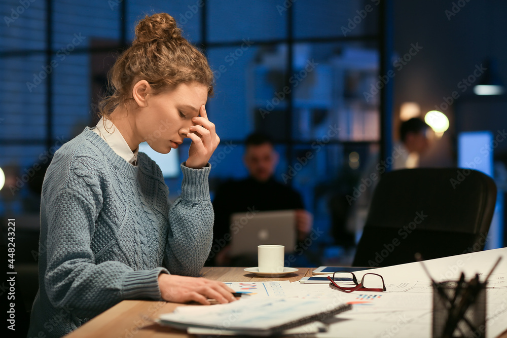 Tired young woman working in office at night