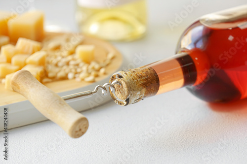 Bottle of wine with corkscrew on table, closeup