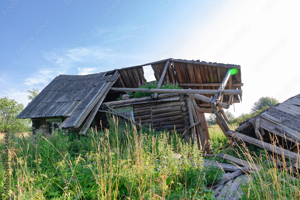 Old wooden rustic ruined abandoned house against a blue sky with white clouds on a bright summer sunny day. Close-up. Scenery