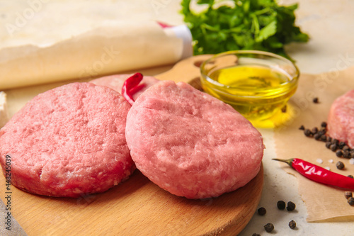 Wooden board with raw cutlets made of fresh forcemeat on table, closeup