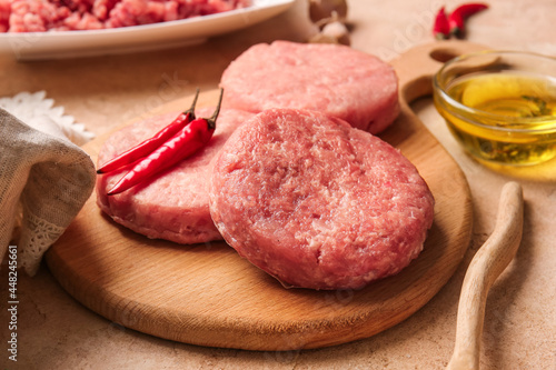 Wooden board with raw cutlets made of fresh forcemeat on table, closeup