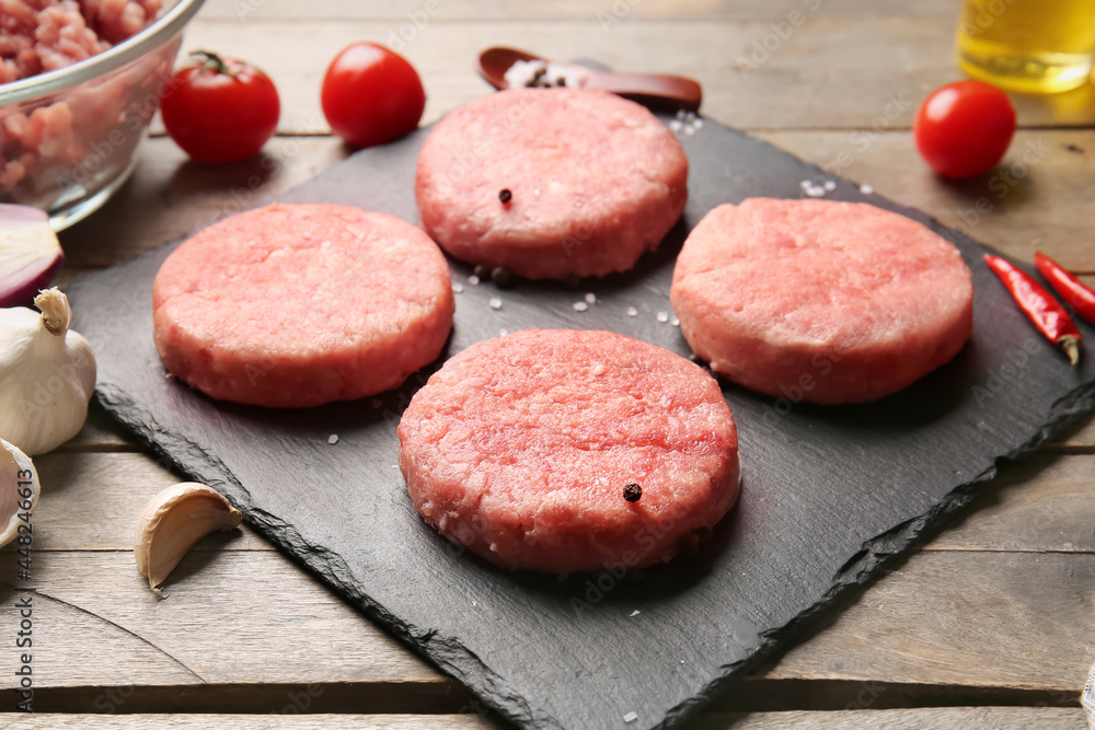 Board with raw cutlets made of fresh forcemeat on wooden background Board with raw cutlets made of fresh forcemeat on wooden background