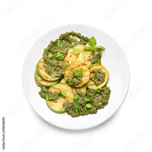 Plate with tasty grilled zucchini and pesto sauce on white background