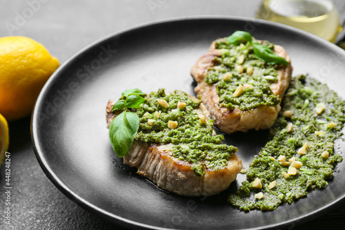 Plate with tasty steaks and pesto sauce on dark background, closeup