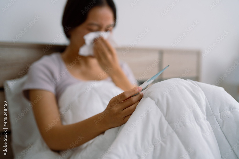 Asian woman she home isolation , she's stressed. She measures her body temperature. Asian woman she home isolation , she's stressed. She measures her body temperature.