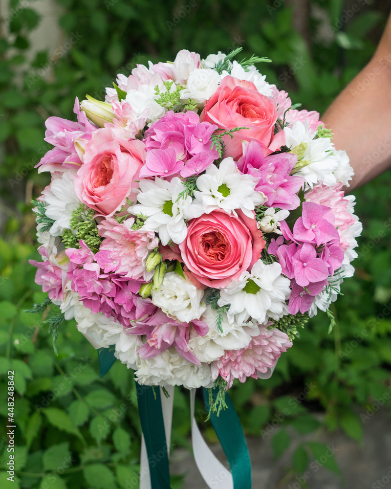 Round wedding bridal bouquet of pink and white flowers on green background, selective focus
