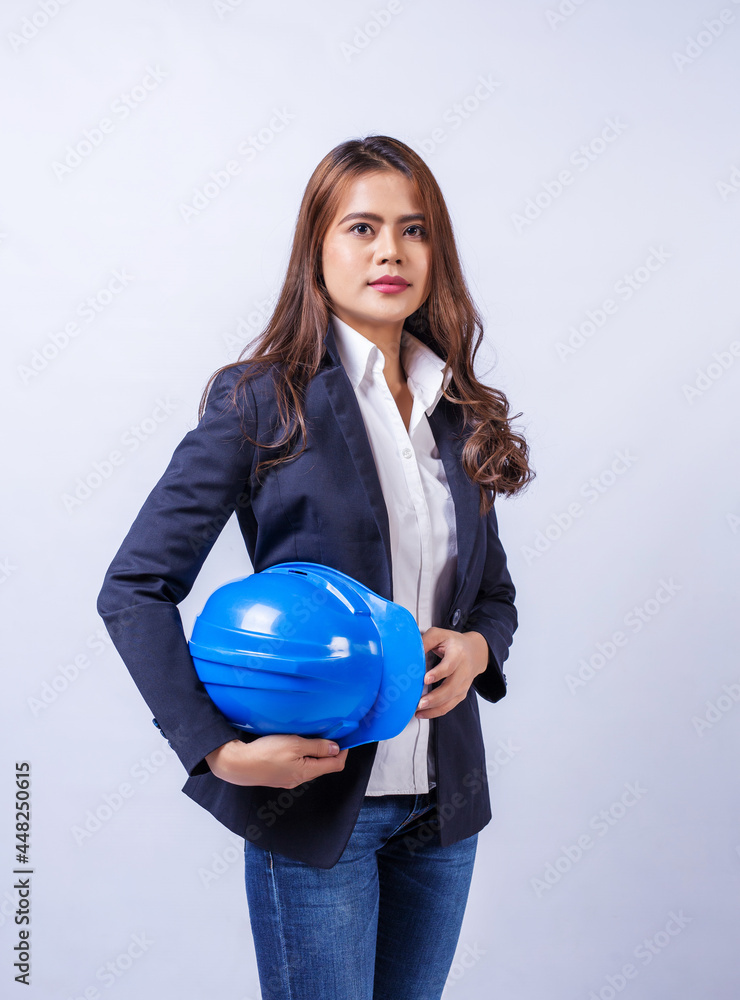 Female engineer with long hair holding a blue helmet on gray background. Female engineer with long hair holding a blue helmet on gray background.