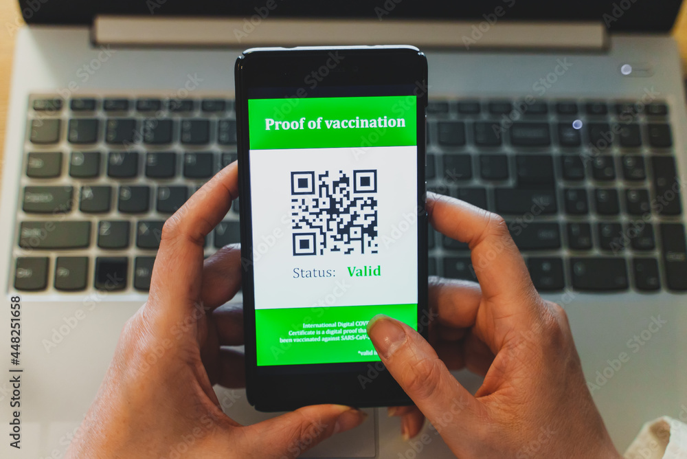 Woman holding smartphone with coronavirus vaccine passport app. Status is valid. Woman holding smartphone with coronavirus vaccine passport app. Status is valid.