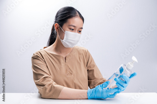 Asian woman wearing protective mask and presenting alcohol antiseptic gel