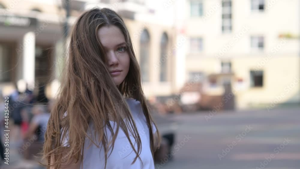 Portrait of Young beautiful woman in a white T-shirt walks on the street in the city. beautiful brunette sexy smiling girl with long hair. Natural beauty woman enjoying day outdoors. Portrait of Young beautiful woman in a white T-shirt walks on the street in the city. beautiful brunette sexy smiling girl with long hair. Natural beauty woman enjoying day outdoors.