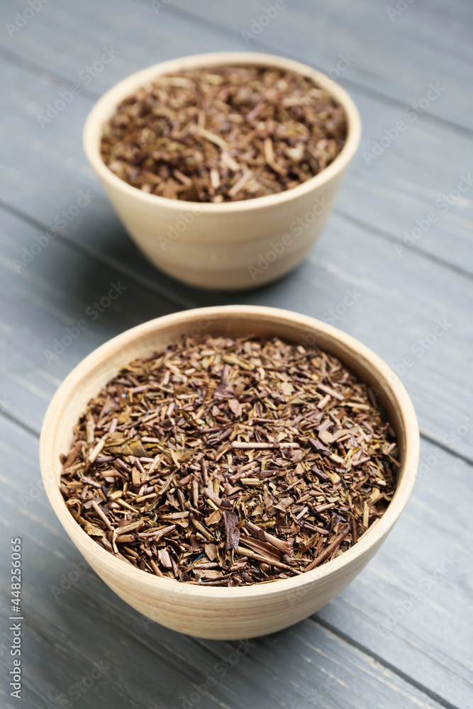 Bowls of dry hojicha green tea on grey wooden background Bowls of dry hojicha green tea on grey wooden background