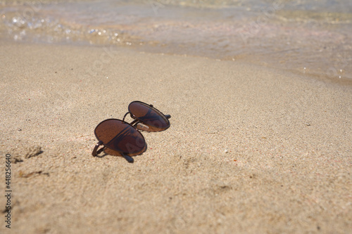 Sunglasses on sand for summer holiday concept.