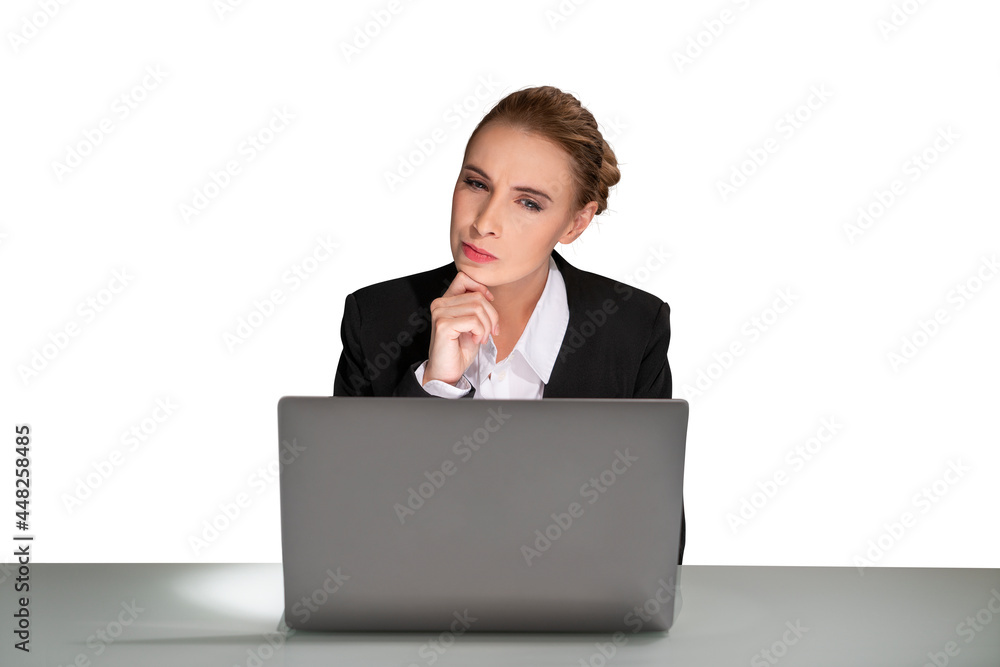 Portrait of attractive thoughtful young business woman in formal clothes sitting at the desk and looking on laptop display. Concept of corporate lifestyle. Hand on chin. isolated over white background Portrait of attractive thoughtful young business woman in formal clothes sitting at the desk and looking on laptop display. Concept of corporate lifestyle. Hand on chin. isolated over white background