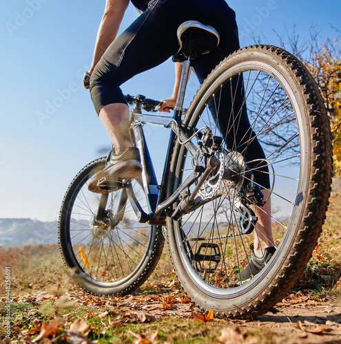 Back view of a man with a bicycle against the blue sky.