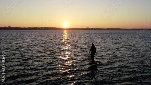 E Foil Sunset boating on the water. Paddleboard, stand-up surfing on electric foil. Aerial drone shot at sunrise. Luxury lifestyle, superyacht water toys.