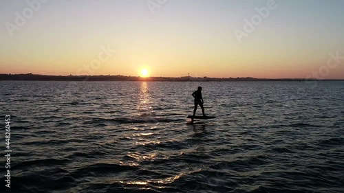 E Foil Sunset boating on the water. Paddleboard, stand-up surfing on electric foil. Aerial drone shot at sunrise. Luxury lifestyle, superyacht water toys.