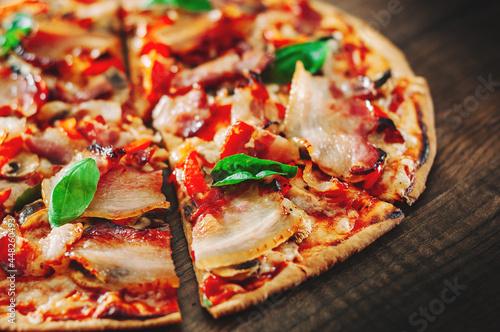 Pizza with Mozzarella cheese, mushrooms, bacon, Tomatoes, pepper, Spices and Fresh Basil. Italian pizza on wooden background