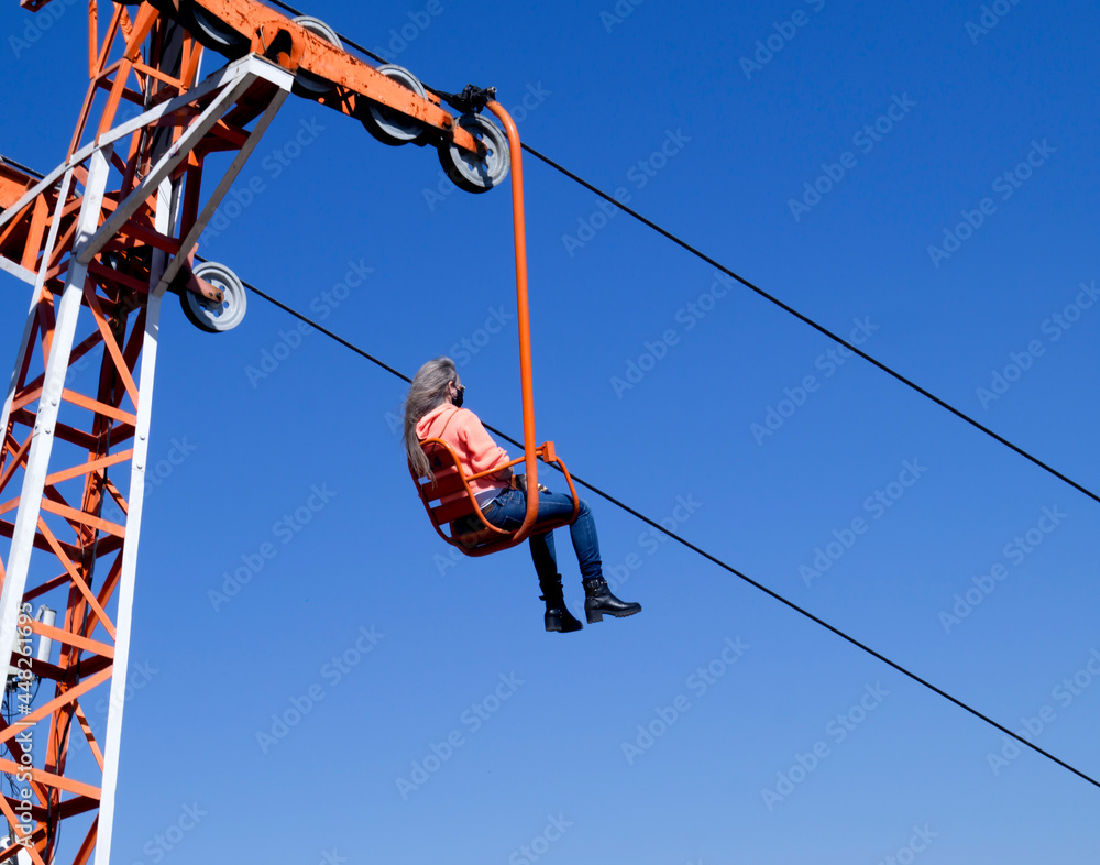 Woman in chair lift going down the mountain, in Serra Negra, São Paulo, Brazil - July 26, 2021 Woman in chair lift going down the mountain, in Serra Negra, São Paulo, Brazil - July 26, 2021