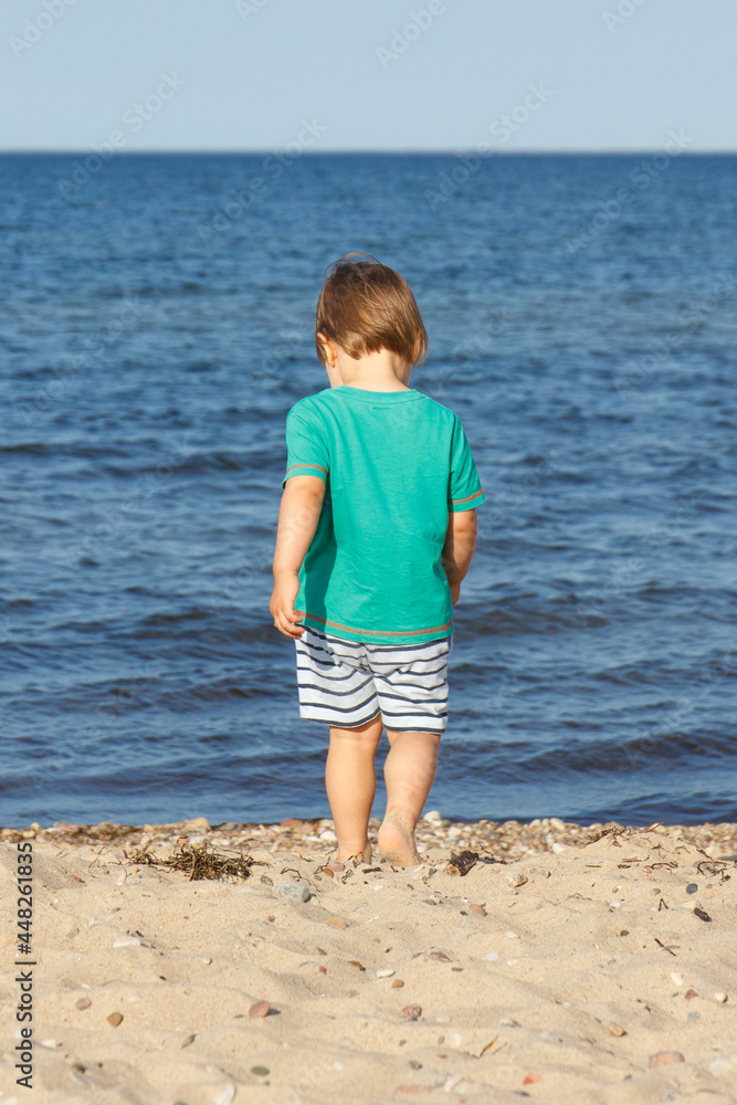 Baby boy walking at summer beach. Vacation time and child development concept Baby boy walking at summer beach. Vacation time and child development concept