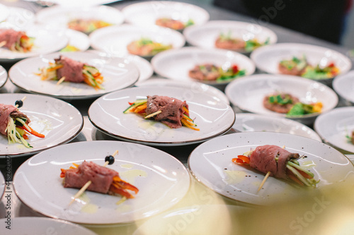 chef is serving meat rolls as starter appetizer filled with fresh veggies on the catering food court event