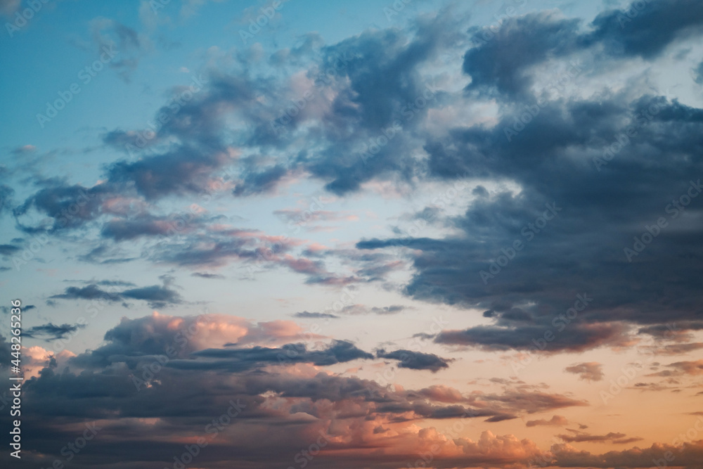The sky is covered with bright blue and orange clouds at sunset. Huge natural sky background with colorful clouds, without any birds. The sky is covered with bright blue and orange clouds at sunset. Huge natural sky background with colorful clouds, without any birds.