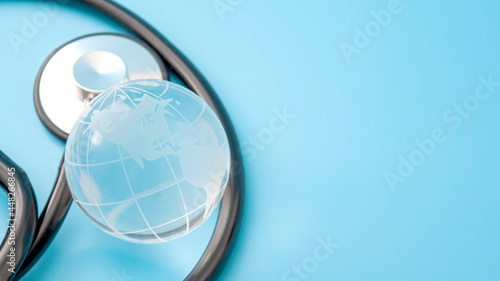 Obraz na płótnie Global health, worldwide healthcare and International medicine research concept with glass globe or planet earth model and stethoscope isolate on blue background with copy space w salonie