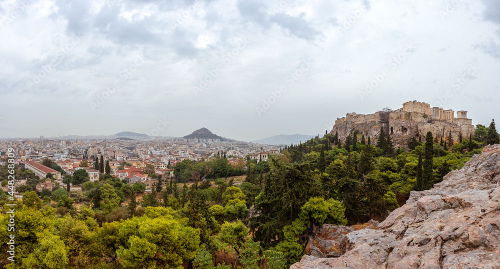 Panorama on Acropolis (Parthenon), mount Lycabettus and Athens old city center architecture in greenery on cloudy dramatic day from rocks of Areopagus - Hill