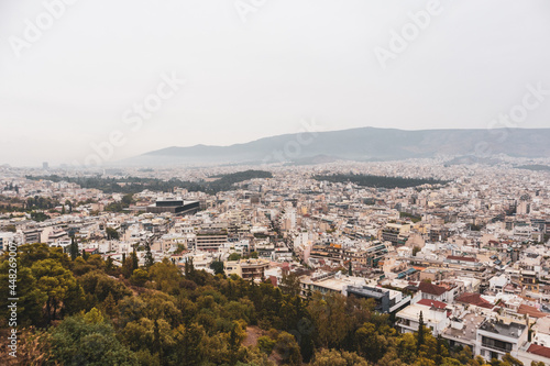 Fototapeta Naklejka Na Ścianę i Meble -  Athens city center streets with white buildings in parks greenery on gray foggy day. Rooftop view from Filopappou Hill park near Acropolis, Greece