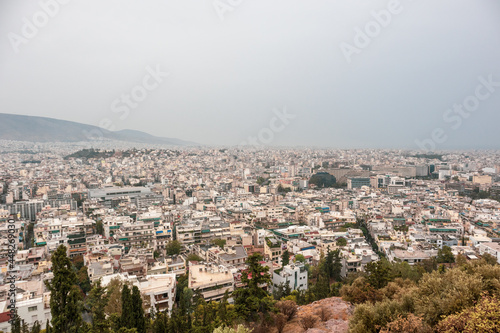 Modern Athens city center streets with white buildings on cloudy foggy day. Rooftop Attica view from Filopappou Hill near Acropolis, Greece
