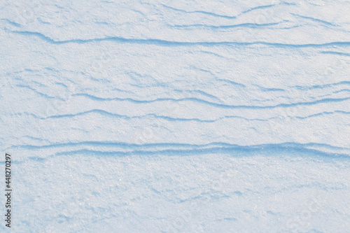 Snowy background, snow-covered surface of the earth after a blizzard in the morning in the sunlight with distinct layers of snow