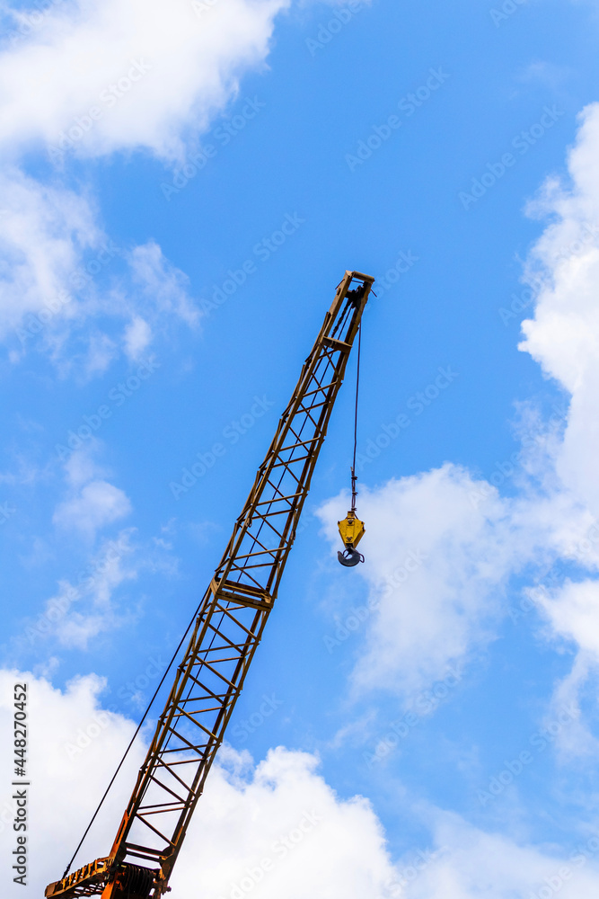 Construction crane on a background of blue sky with white clouds