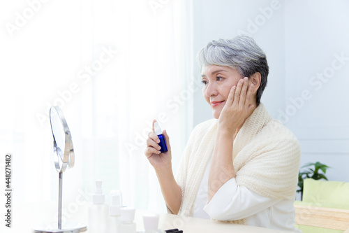 Senior Asia woman is holding a bottle and doing skin care.