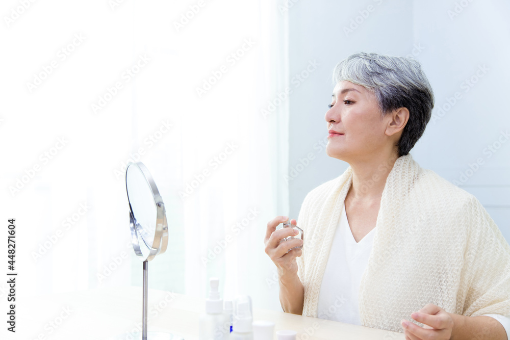 Senior Asia woman is spraying perfume. Senior Asia woman is spraying perfume.