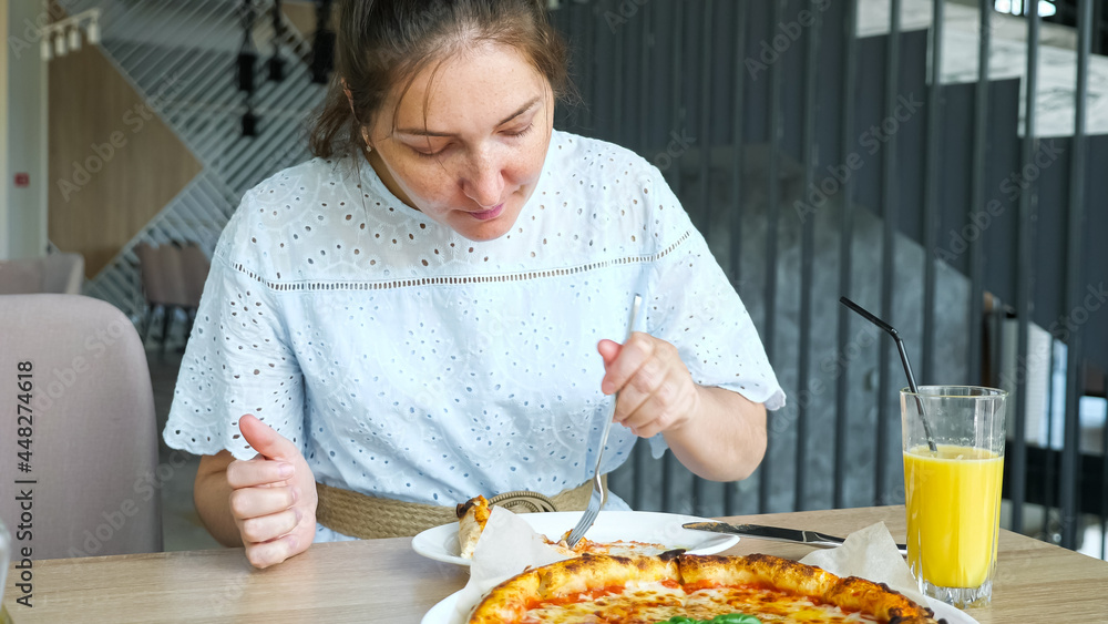 Lady eats pizza enjoying in the restaurant.