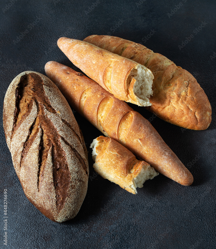 Bread loaves on a dark background. Vertical orientation, close-up.