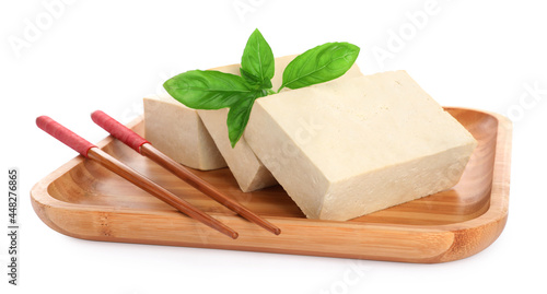 Wooden plate with delicious raw tofu, basil and chopsticks on white background