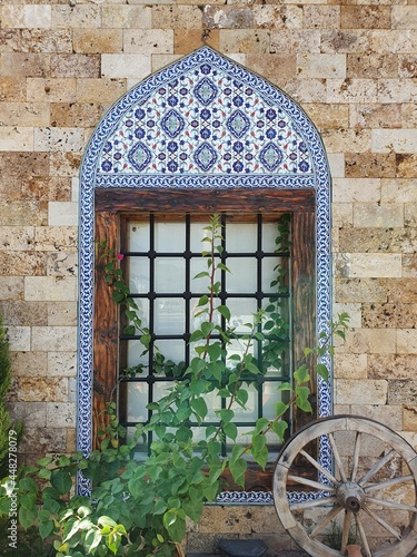 Window of an old building in Turkish style. The building is built of stone. The framing is made of painted tiles.