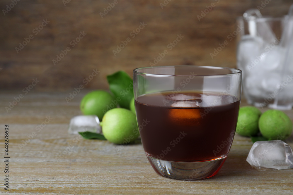 Delicious liqueur with ice and green walnuts on wooden table. Space for text Delicious liqueur with ice and green walnuts on wooden table. Space for text