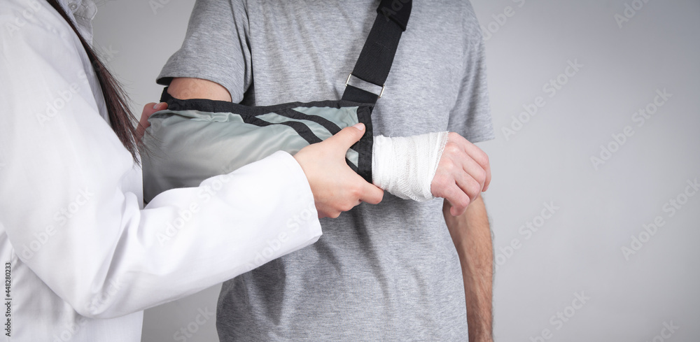 Caucasian doctor putting arm sling on patient hand.