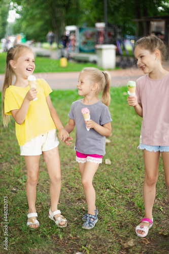 Little Girls Walking Outside In Park Eating Ice Cream. Siblings Eating Ice Cream And Laughing