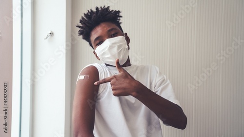 Leinwand Poster African American teenager showing COVID-19 vaccine bandage merrily in concept of coronavirus vaccination program to vaccinate citizen