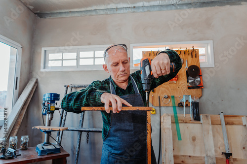 adult man in his wood workshop, using electric screwdriver
