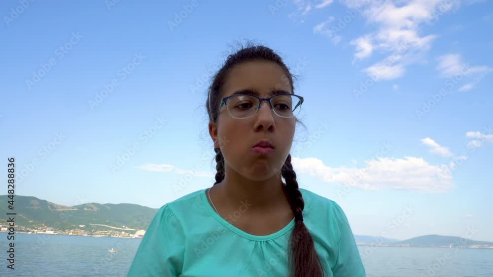 Girl eating potato chips. On the seashore. Tanned skin. Fast food. Against the background of the sea and mountains. Turquoise T-shirt. Close-up. Girl eating potato chips. On the seashore. Tanned skin. Fast food. Against the background of the sea and mountains. Turquoise T-shirt. Close-up.
