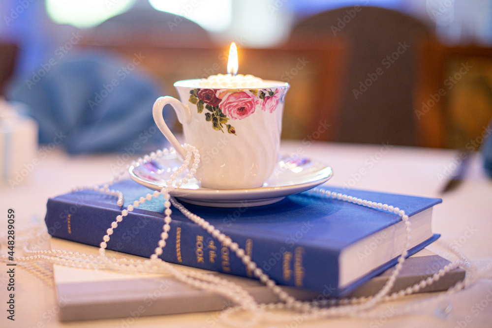 Tea cup and plate with hand painted roses draped in pearls on a blue bible Tea cup and plate with hand painted roses draped in pearls on a blue bible