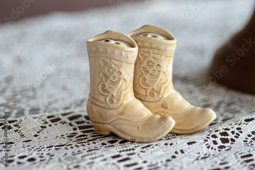 Miniature glass white cowboy boots figurines on white lace surface