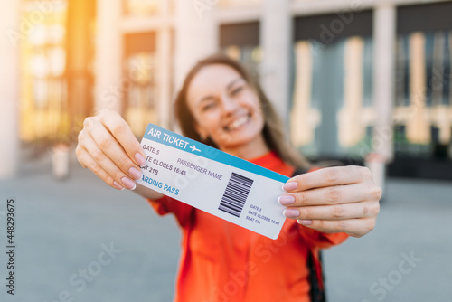 Caucasian girl joyful holding an air ticket for the plane and travel in her hands